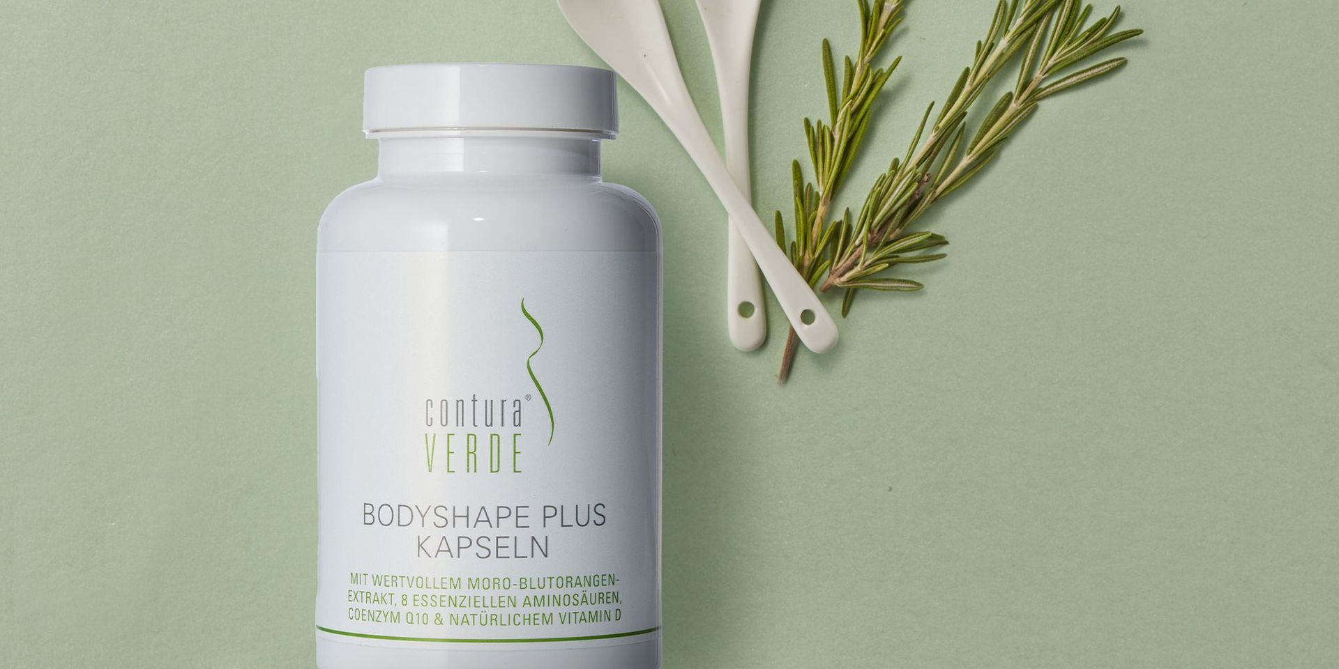 Contura Verde Bodyshape Plus Kapseln auf grünem Hintergrund mit Kräutern und Löffeln