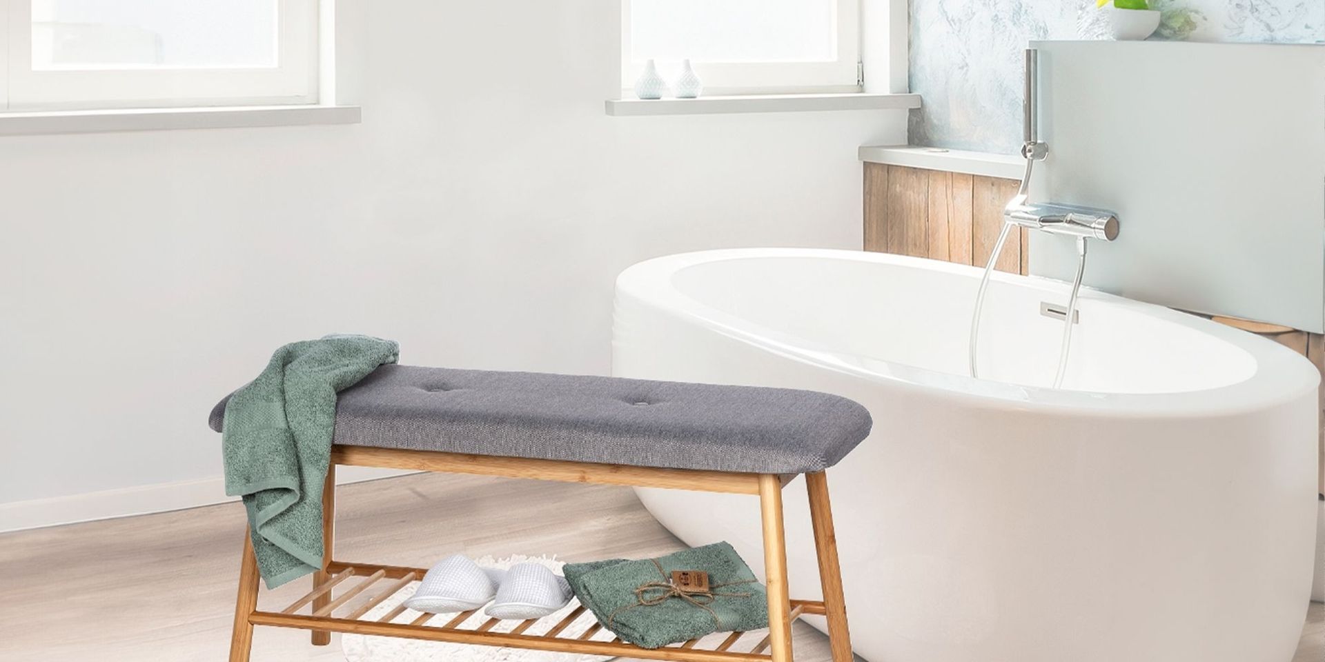 Modernes Badezimmer mit grauer Sitzbank und grünen Handtüchern neben einer weißen Badewanne